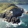 Two lighthouse buildings perched on a rocky cliff dropping into the ocean